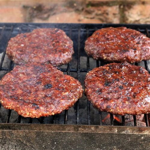 Hand-made burgers sizzling on a BBQ.