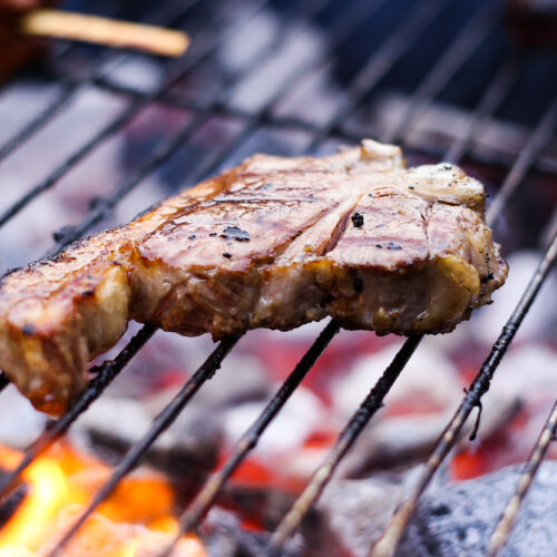 Pork steak cooking on a BBQ.