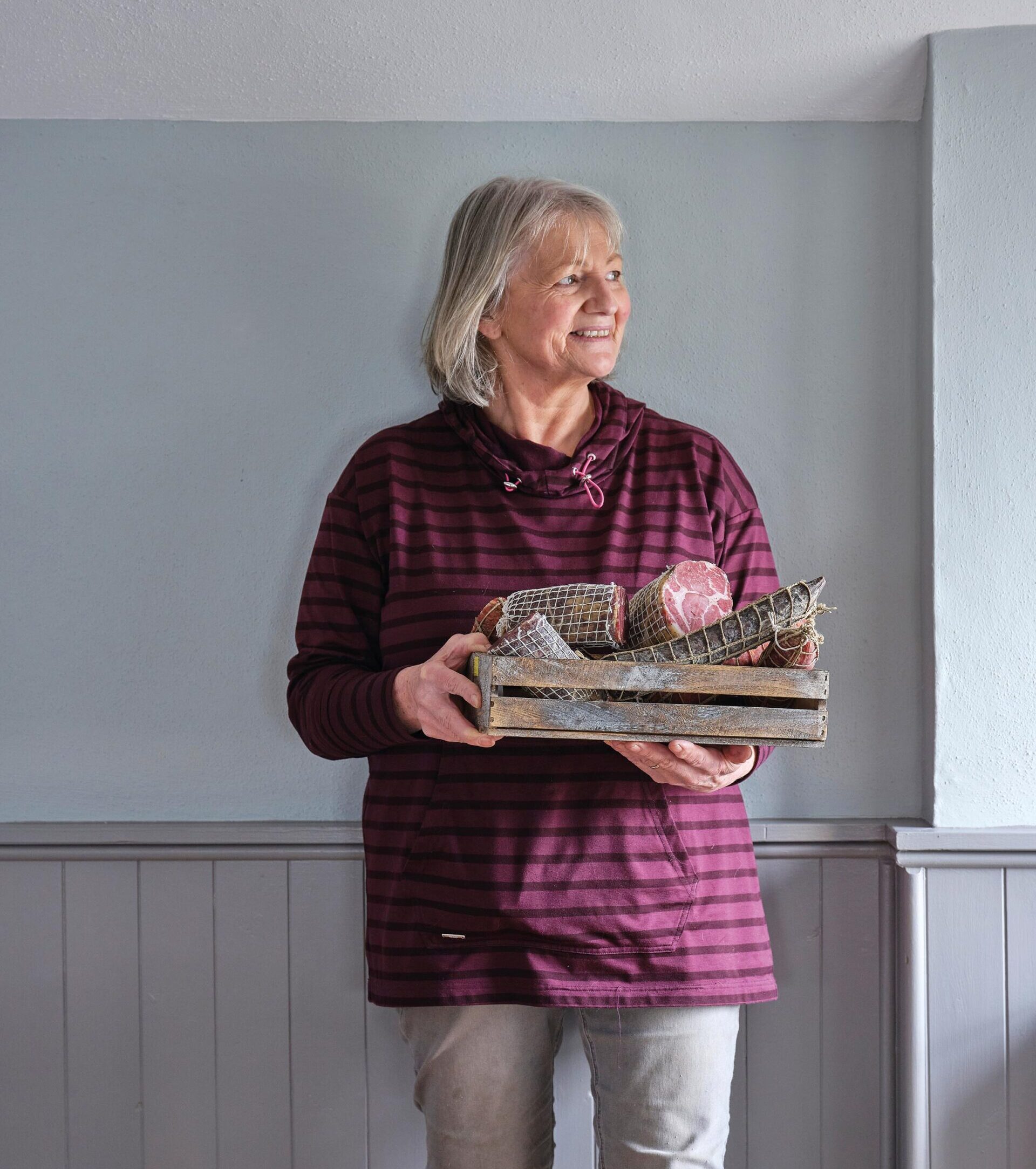 A female West country producer holding a basket of charcuterie products